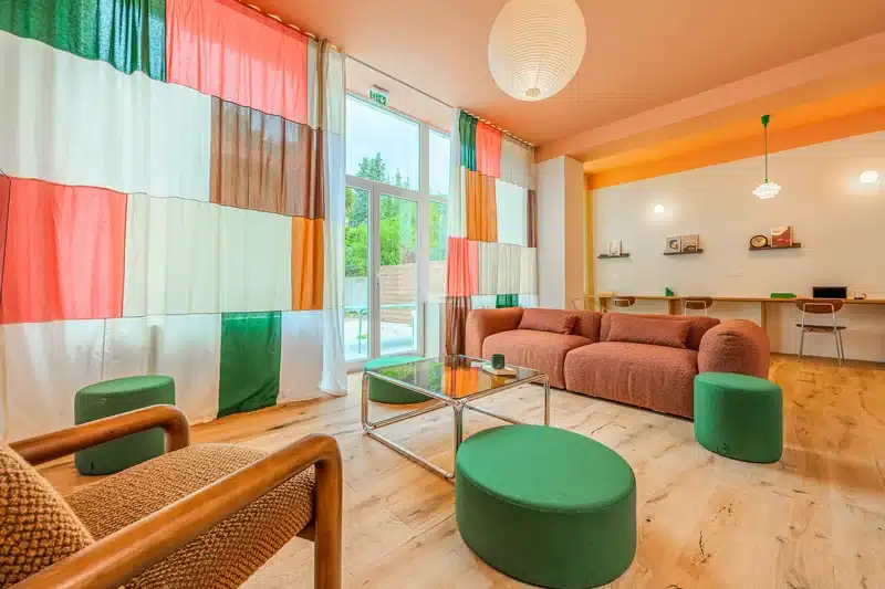 Salon avec canapé et poufs verts du coliving Maison Bourgogne à Lille Vauban