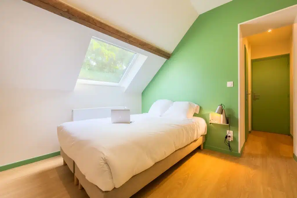 Chambre mansardée avec velux et mur vert, coliving Maison République Lille